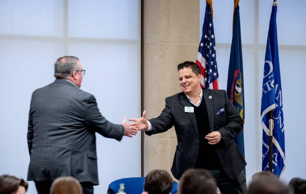 Alumni Board President shaking hands with speaker Jon Husby at the Secchia Breakfast Lecture on Jan 27, 2023